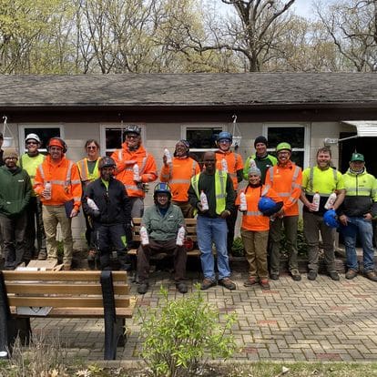 Group of men in orange vests holding bottles.