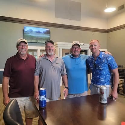 Four men smiling in a room.