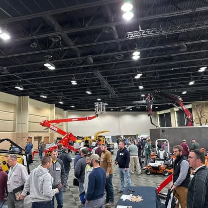 Trade show with machinery and attendees indoors.