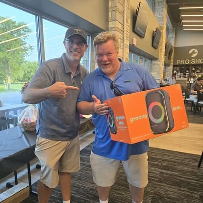 Two men with a speaker box indoors.