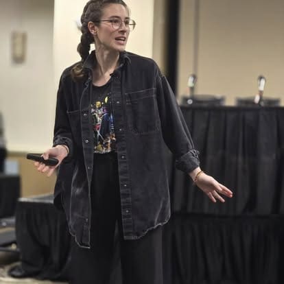 Person speaking at a conference with microphone.
