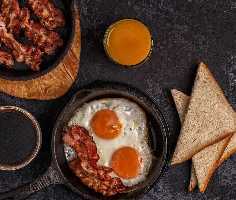 Breakfast with bacon, eggs, toast, and juice.
