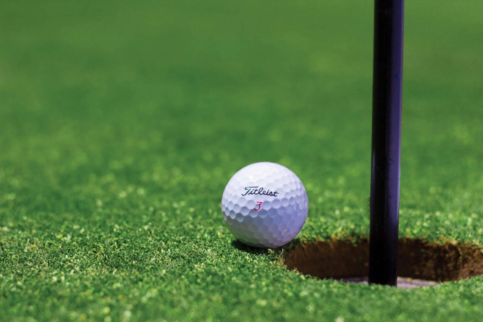 Golf ball near hole on green grass.