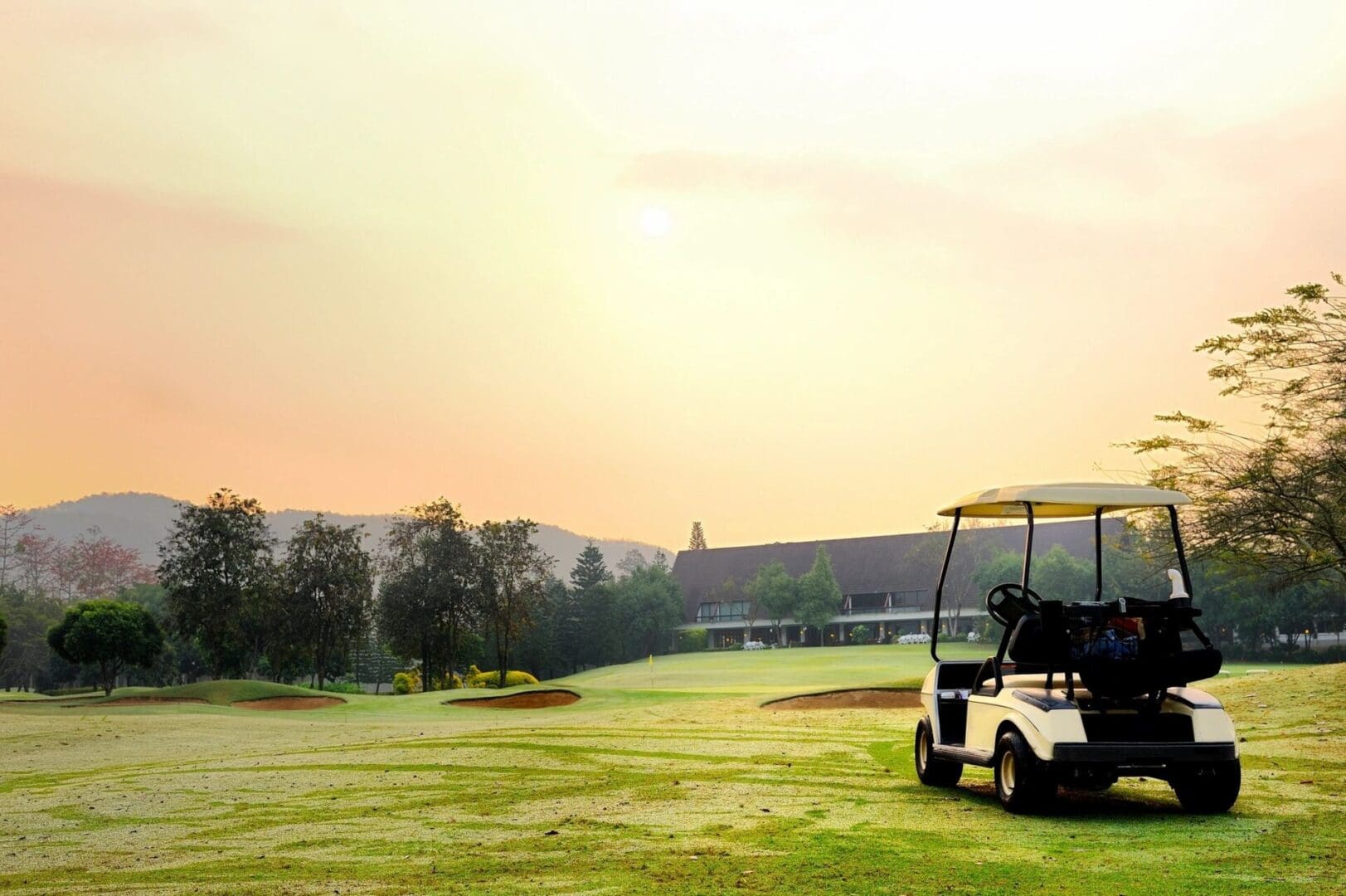 Golf cart on course at sunrise.