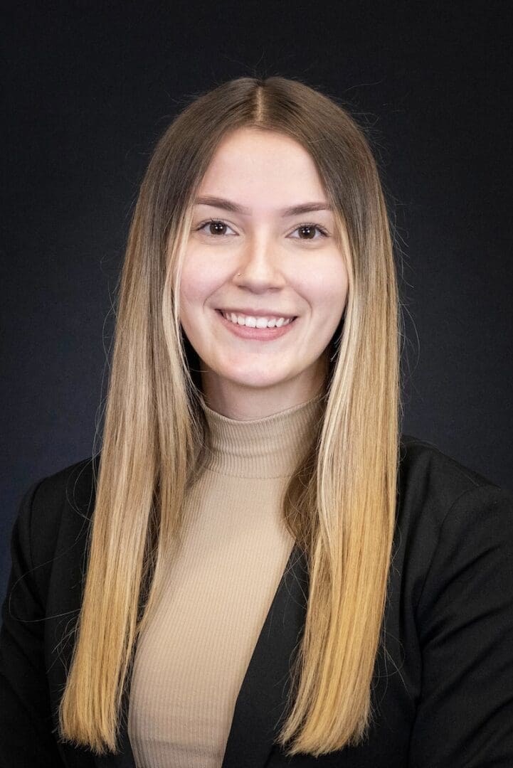 Smiling woman with long hair, black background.