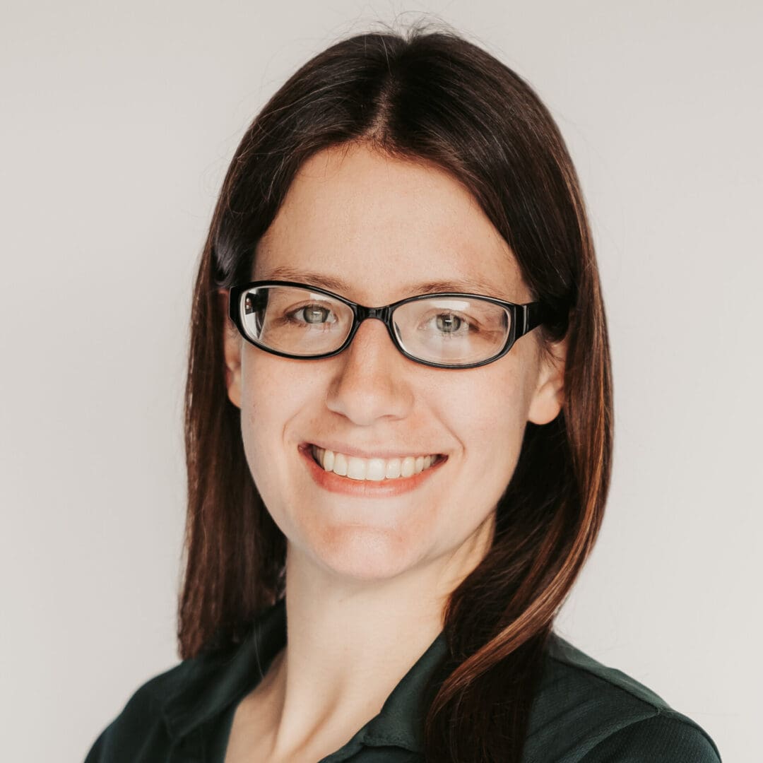 Smiling woman with glasses and dark hair.