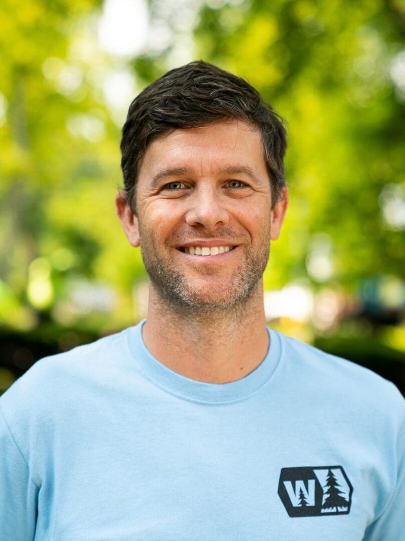 Smiling man outdoors in a blue shirt.