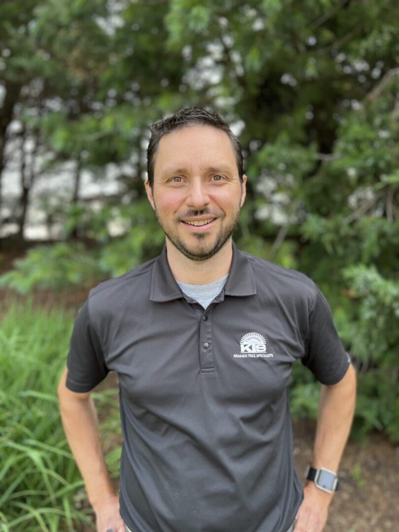 Man smiling outdoors in dark polo shirt.